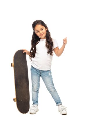 cute latin kid showing thumb up while holding penny board isolated on whiteの写真素材