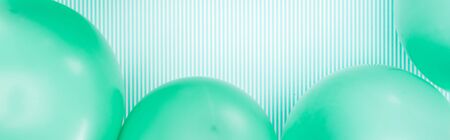 Panoramic shot of green balloons on blue and white striped backgroundの写真素材