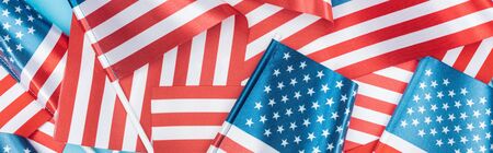 panoramic shot of american flags stacked on blue backgroundの写真素材