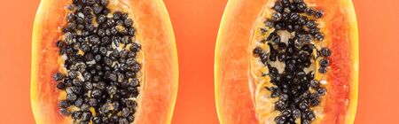 panoramic shot of papaya halves with black seeds isolated on orangeの写真素材
