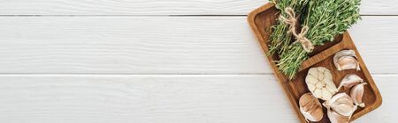 panoramic shot of board with garlic cloves and thyme on white wooden tableの写真素材