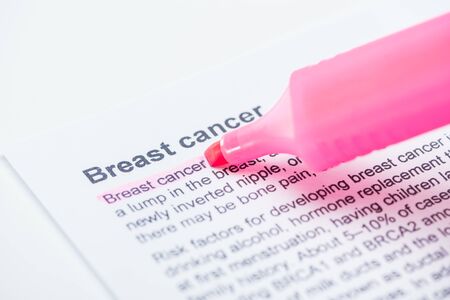 close up view of print newspaper with breast cancer article and pink marker on white background