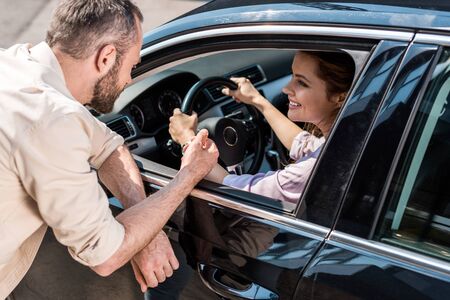Overhead view of man standing near happy woman holding steering wheel in carの写真素材