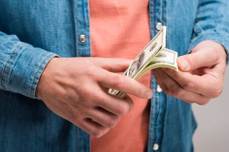Cropped view of man counting money isolated on a yellow backgroundの写真素材