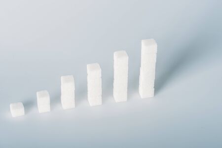 White sugar cubes arranged in stacks on grey background with copy space