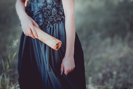 Cropped view of woman in black witch costume standing with scroll in handの写真素材
