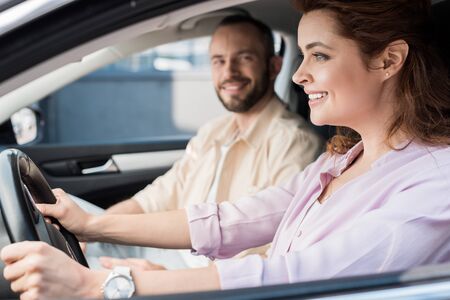 Selective focus of happy woman driving car near handsome man