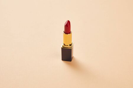 Single opened tube of red lipstick on beige backgroundの写真素材