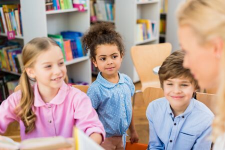 Selective focus of happy multicultural kids smiling near womanの写真素材