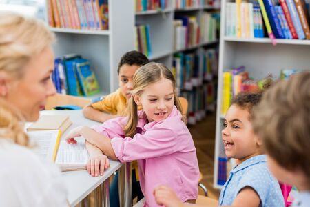 Selective focus of kid looking at cheerful African American girl near multicultural boys