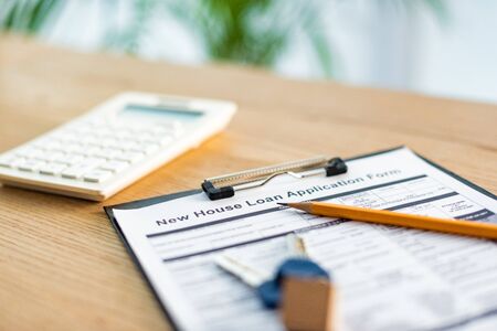 Selective focus of clipboard with document near pencil, keys and calculator