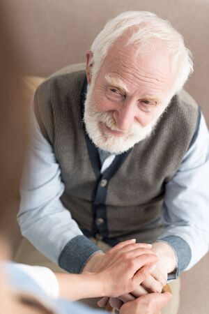High angle view of smiling senior man, holding woman handsの写真素材