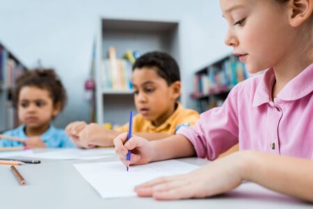 Selective focus of cute kid drawing near African American childrenの写真素材
