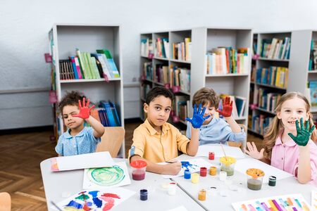 Cheerful multicultural kids showing colorful hands with gouache paintの写真素材
