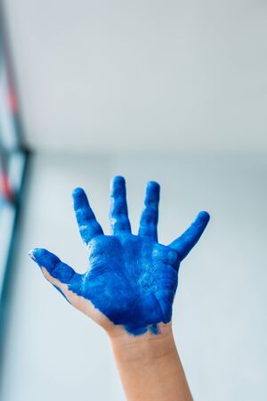 Cropped view of kid showing painted hand with blue gouache paintの写真素材
