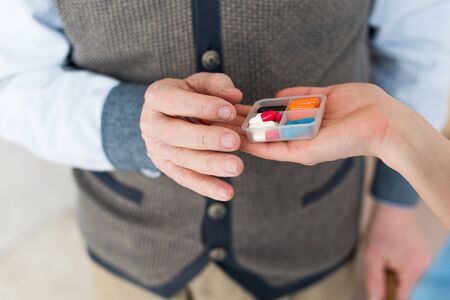 Cropped view of woman hand giving pills to elderly man
