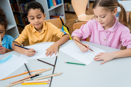 Cute multicultural children drawing on papers with color pencilsの写真素材