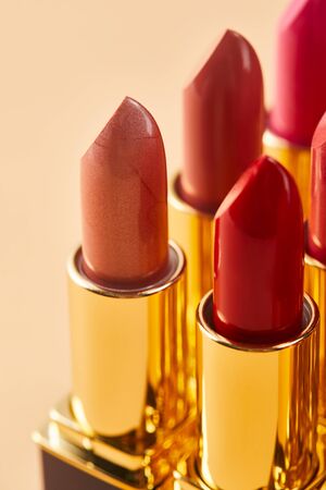 Close up of various red shades of lipstick in tubes on beige backgroundの写真素材