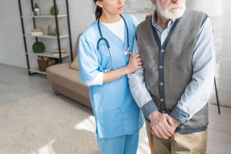 Cropped view of grey haired man standing with nurse in bright roomの写真素材