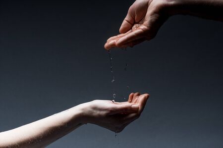 Cropped view of man and woman with water drops on dark backgroundの写真素材
