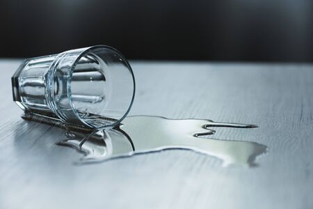 Glass with spilled water on textured wooden surface