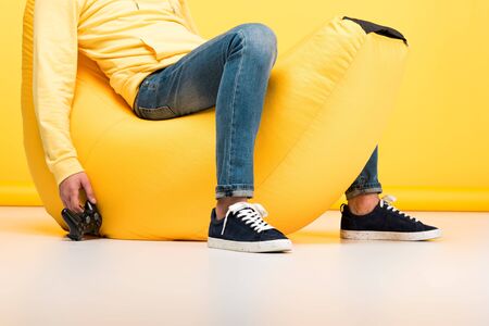 Cropped view of man sitting on bean bag chair with joystickの写真素材