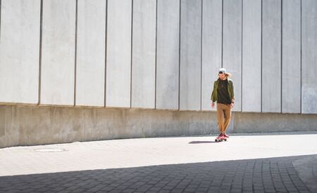 Adult man riding on skateboard near concrete wall