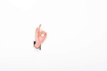 Man showing ok sign from hole in paper wall on white background with copy spaceの写真素材