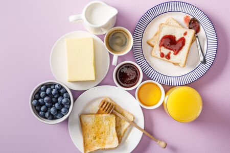 Top view of served breakfast with cup of coffee and orange juice on violet backgroundの写真素材