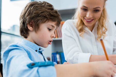 Selective focus of cute kid drawing near happy woman