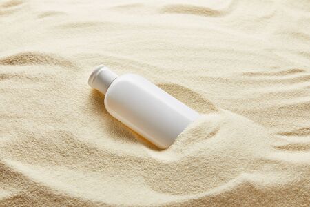 Sunblock moisturizing lotion in white bottle in sand