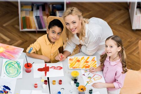 Overhead view of cheerful teacher smiling with happy multicultural kids
