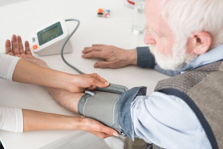 Cropped view of nurse measuring blood pressure of senior manの写真素材