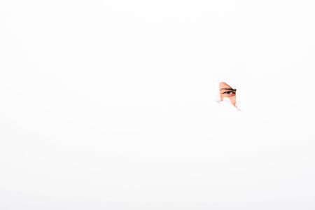 Man looking out from hole in paper wall on white background with copy spaceの写真素材