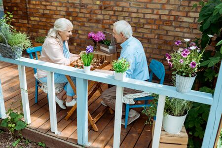 Happy retired couple playing chess while sitting on terraceの写真素材
