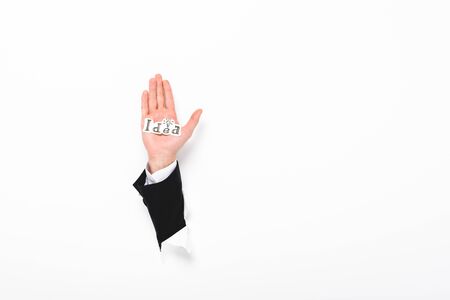 Cropped view of man holding paper with idea word from hole in wall on white background with copy spaceの写真素材