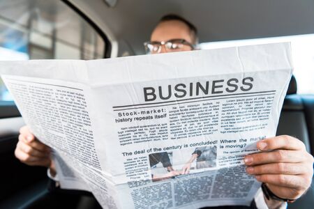 Selective focus of man reading business newspaper in carの写真素材