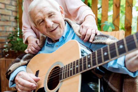 Cropped view of senior woman near happy retired husband playing acoustic guitarの写真素材