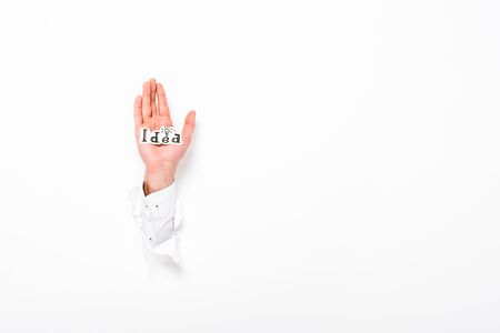 Cropped view of man holding paper with idea word from hole in wall on white background with copy spaceの写真素材