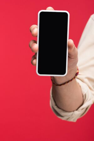 Cropped view of man holding smartphone with blank screen isolated on pink backgroundの写真素材