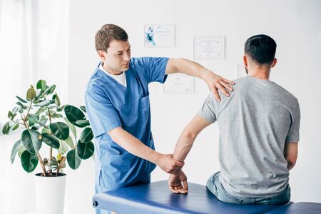 Physiotherapist massaging arm of patient on massage table in hospitalの写真素材