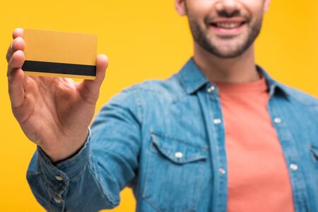 Cropped view of man holding credit card with copy space isolated on yellow background