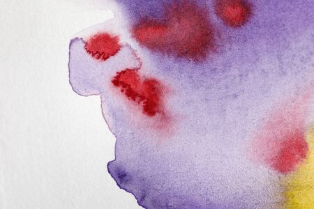 Close up view of yellow, purple and red watercolor paint spills on white backgroundの写真素材