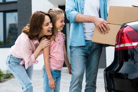 Cropped view of man holding boxes near happy kid and wife backgroundの写真素材