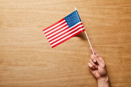 Cropped view of man holding American flag on wooden backgroundの写真素材