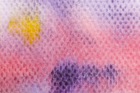 Close up view of yellow and purple watercolor paint spills on textured backgroundの写真素材