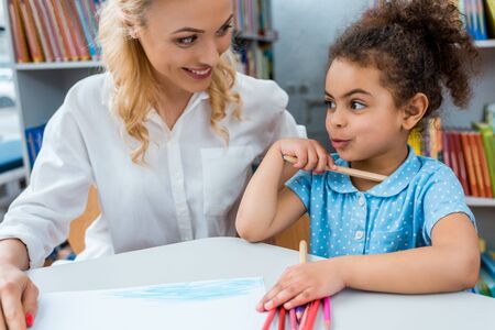 Selective focus of cheerful woman looking at happy African American childの写真素材