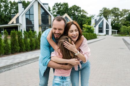 Back view of kid hugging happy parents on streetの写真素材