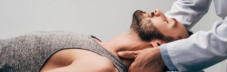Panoramic shot of chiropractor massaging neck of man on grey backgroundの写真素材