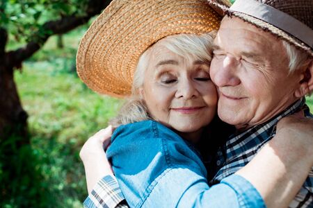 Cheerful senior woman hugging happy retired husband with closed eyesの写真素材